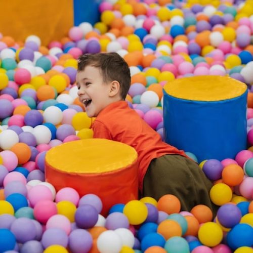 [freepicdownloader.com]-happy-little-boy-has-fun-jumping-into-dry-pool-with-colorful-balls-kid-boy-is-playing-having-good-time-game-room-with-colorful-balls-normal